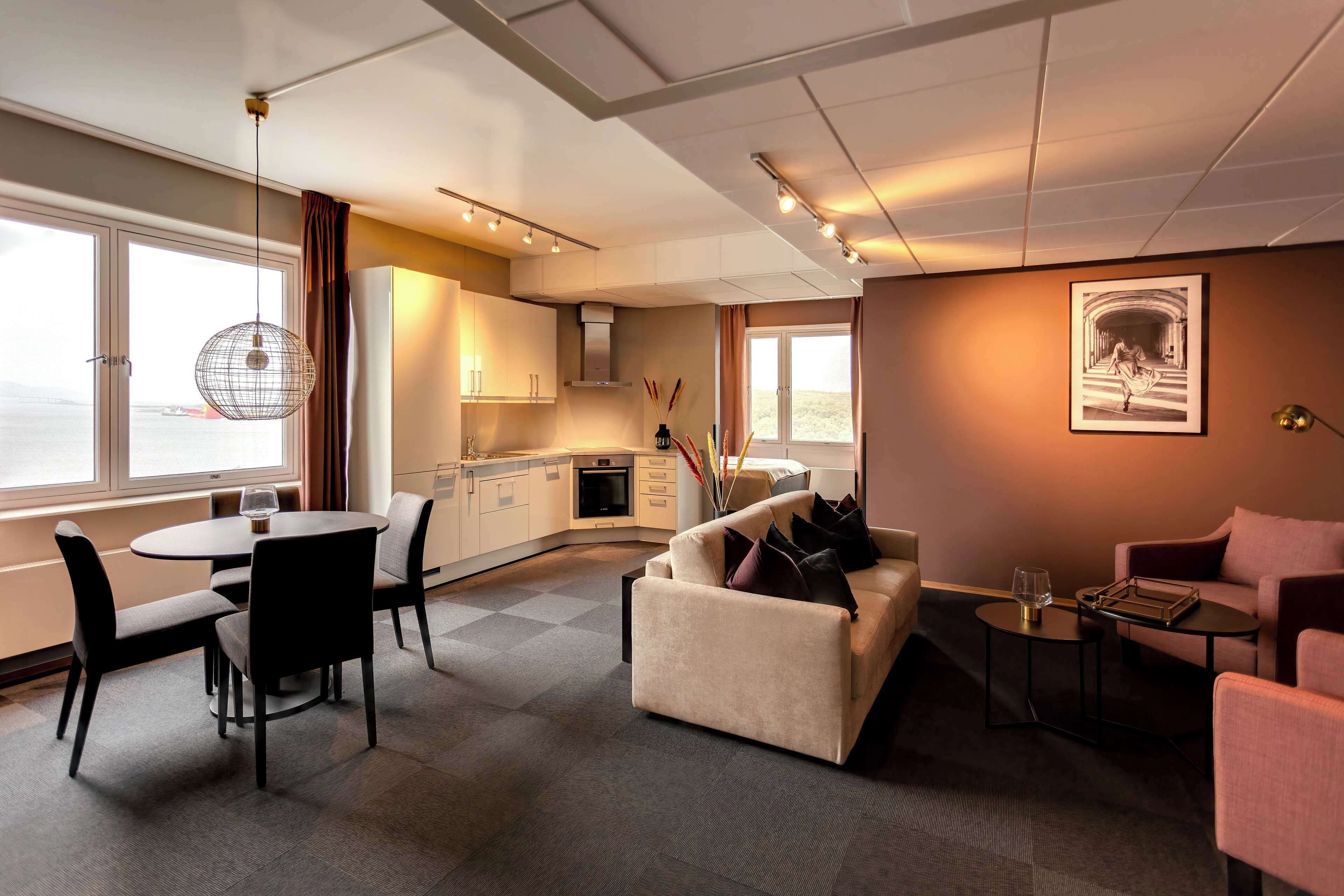 Una habitación de hotel moderna con comedor, sofá y cocina.
