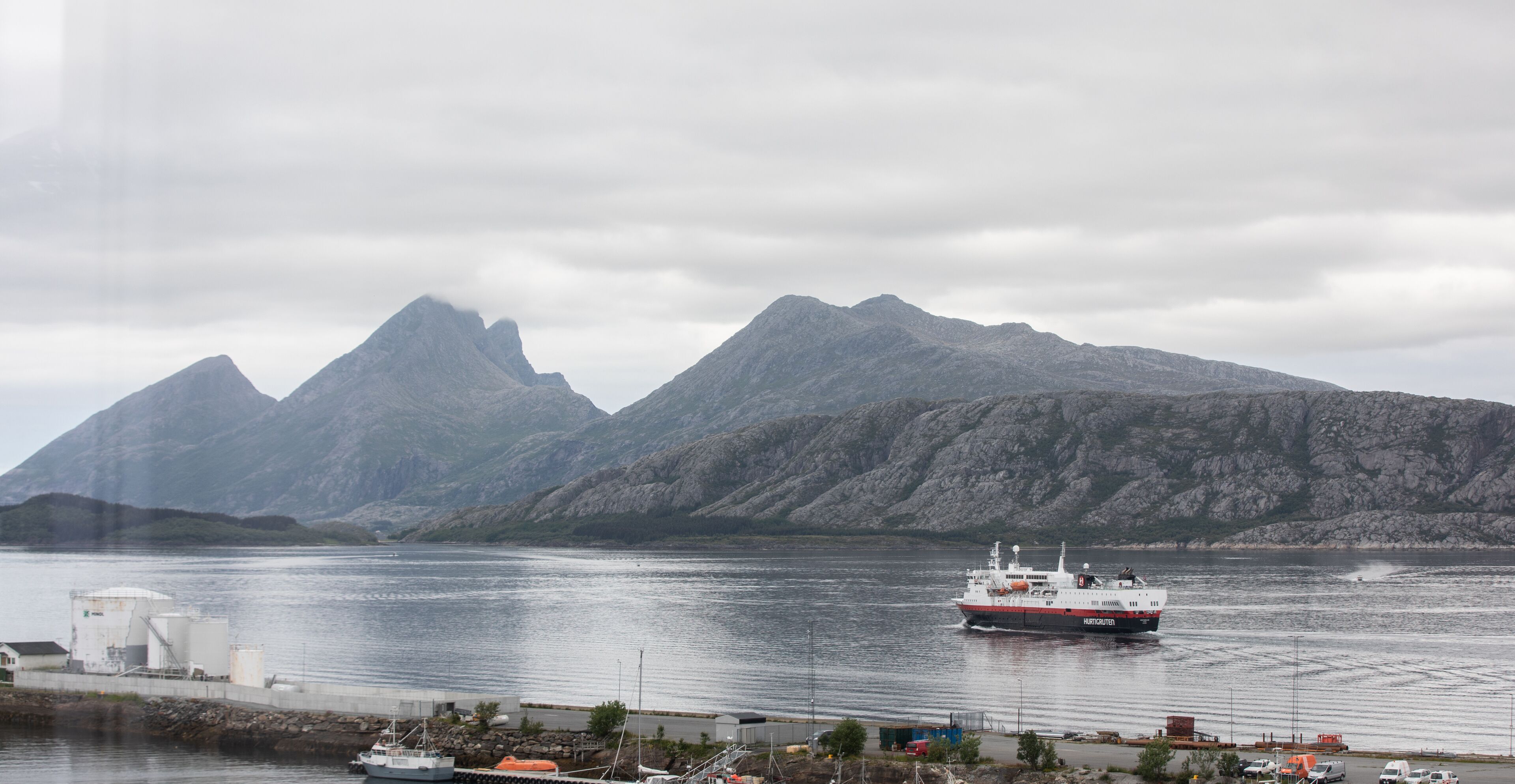Een veerboot afgemeerd in een haven, met bergen op de achtergrond.