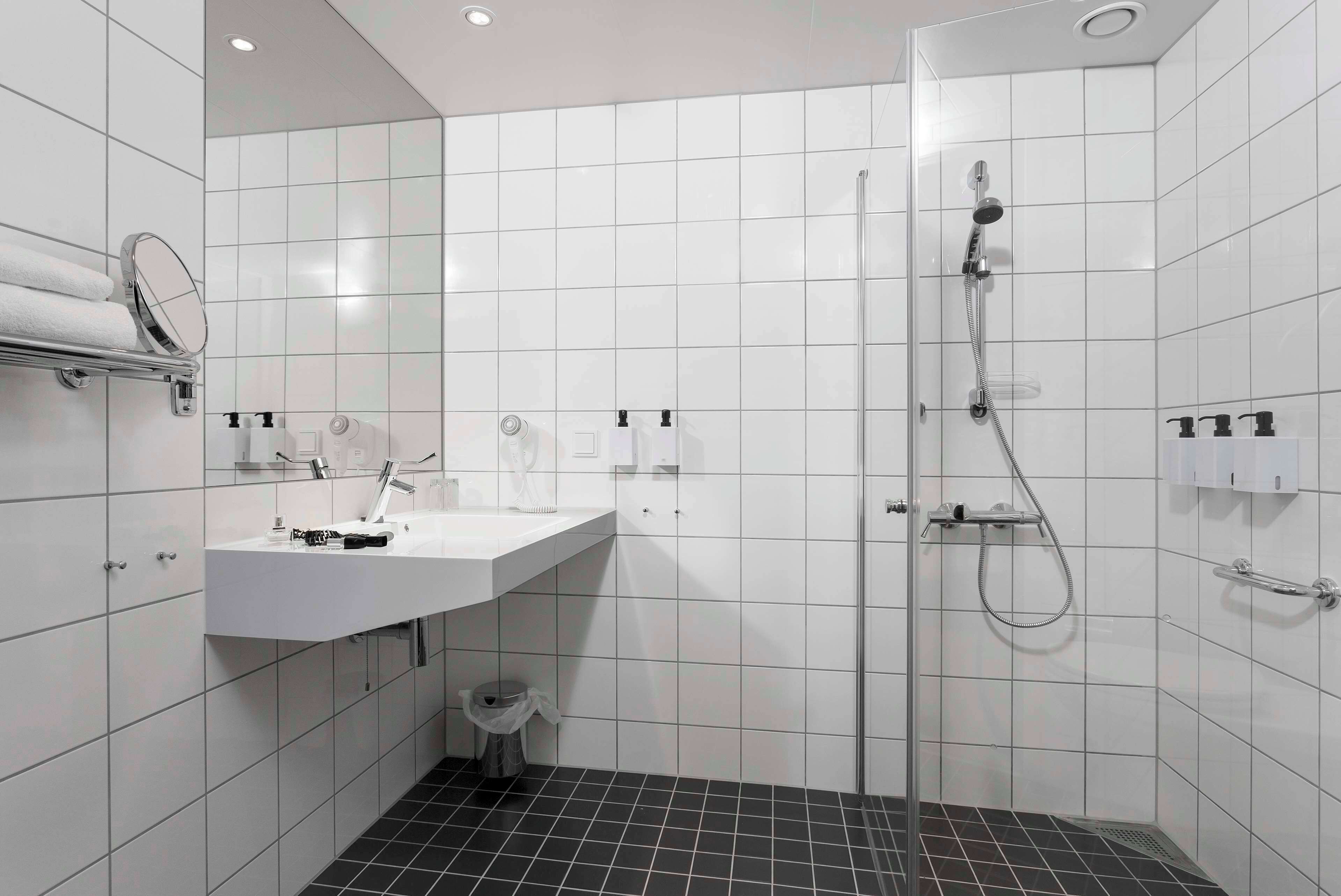 A modern bathroom with a white sink, mirror, and shower.