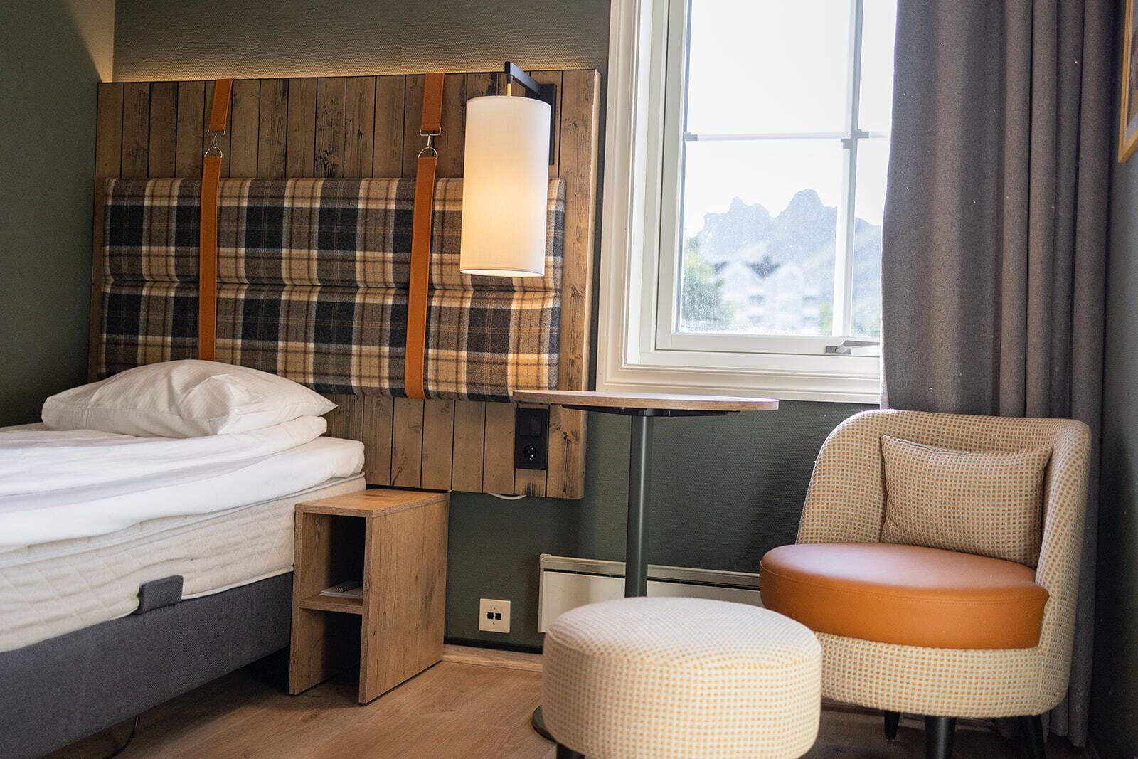 A bedroom with a bed, a chair, a small table, and a window with a view.