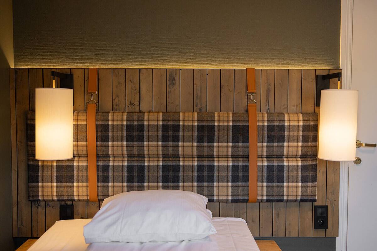 A bedroom with a wooden headboard, two bedside lamps, and a bed with white bedding.