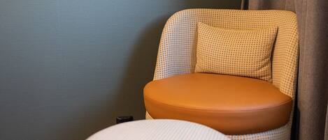 A modern chair with a checkered pattern and a brown seat, positioned against a textured wall.