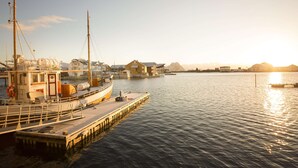 Uma marina com um barco atracado, um cais e edifícios ao fundo.