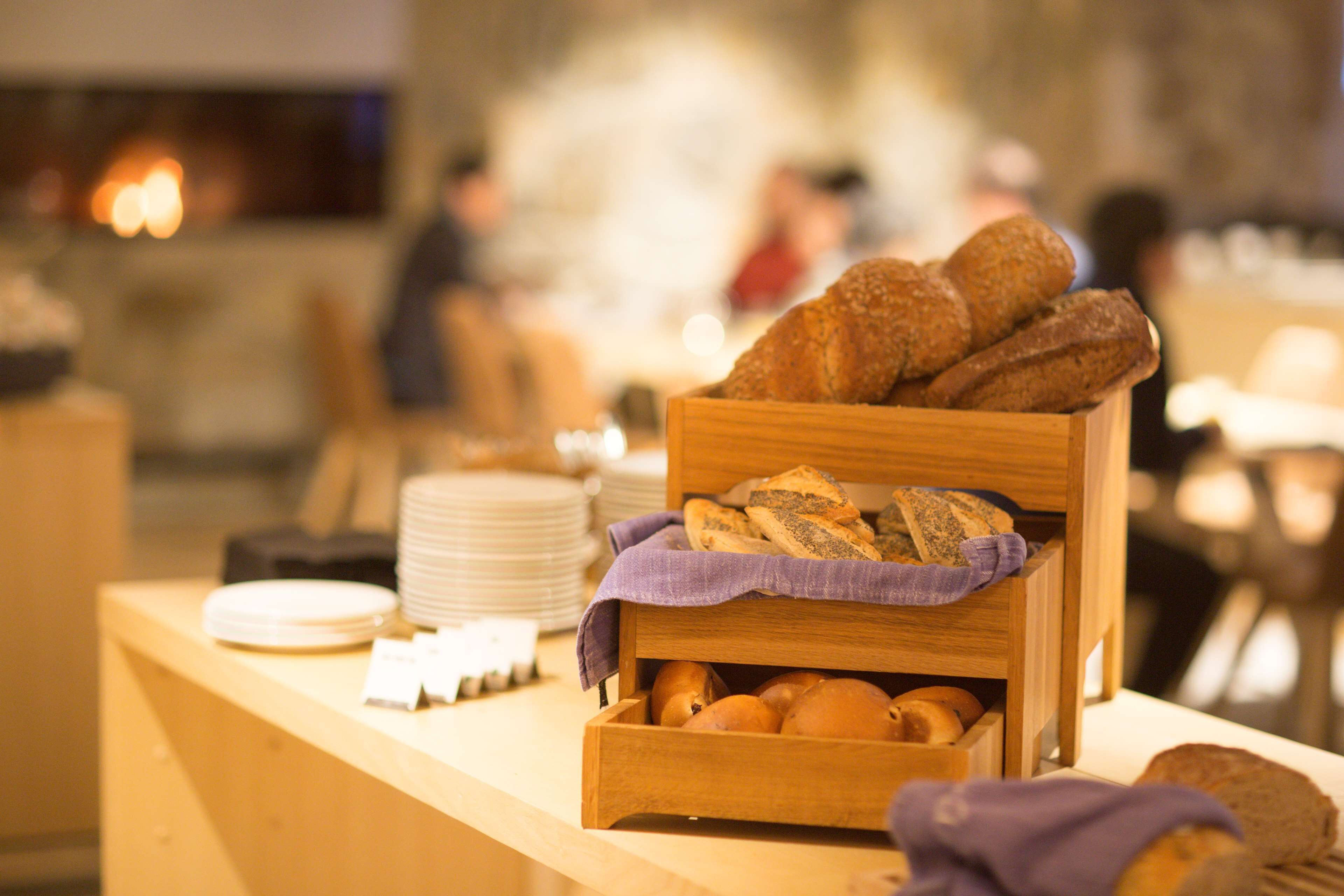 A wooden counter with a basket of bread and a stack of white plates.