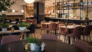 A modern restaurant with round tables, cushioned chairs, and potted plants. - Quality Hotel Grand Tromso (Tromso)