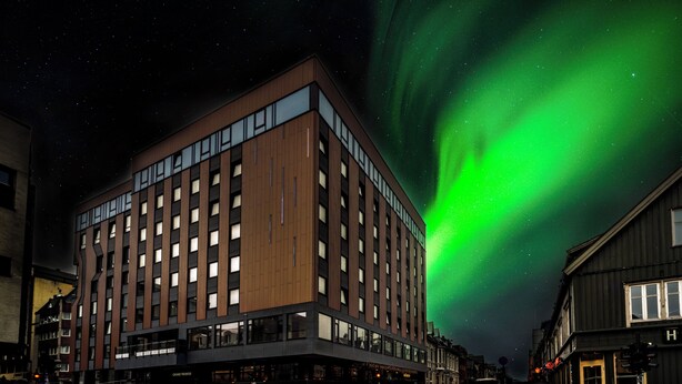 A modern building with a flat roof and large windows, located at a street corner with a crosswalk. - Quality Hotel Grand Tromso (Tromso)