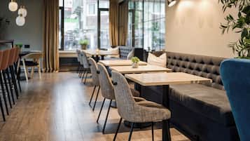 A modern dining area with wooden flooring, a long table, and cushioned seating.