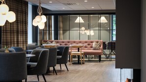 A modern interior with a sofa, chairs, tables, and hanging lights. - Quality Hotel Grand Tromso (Tromso)