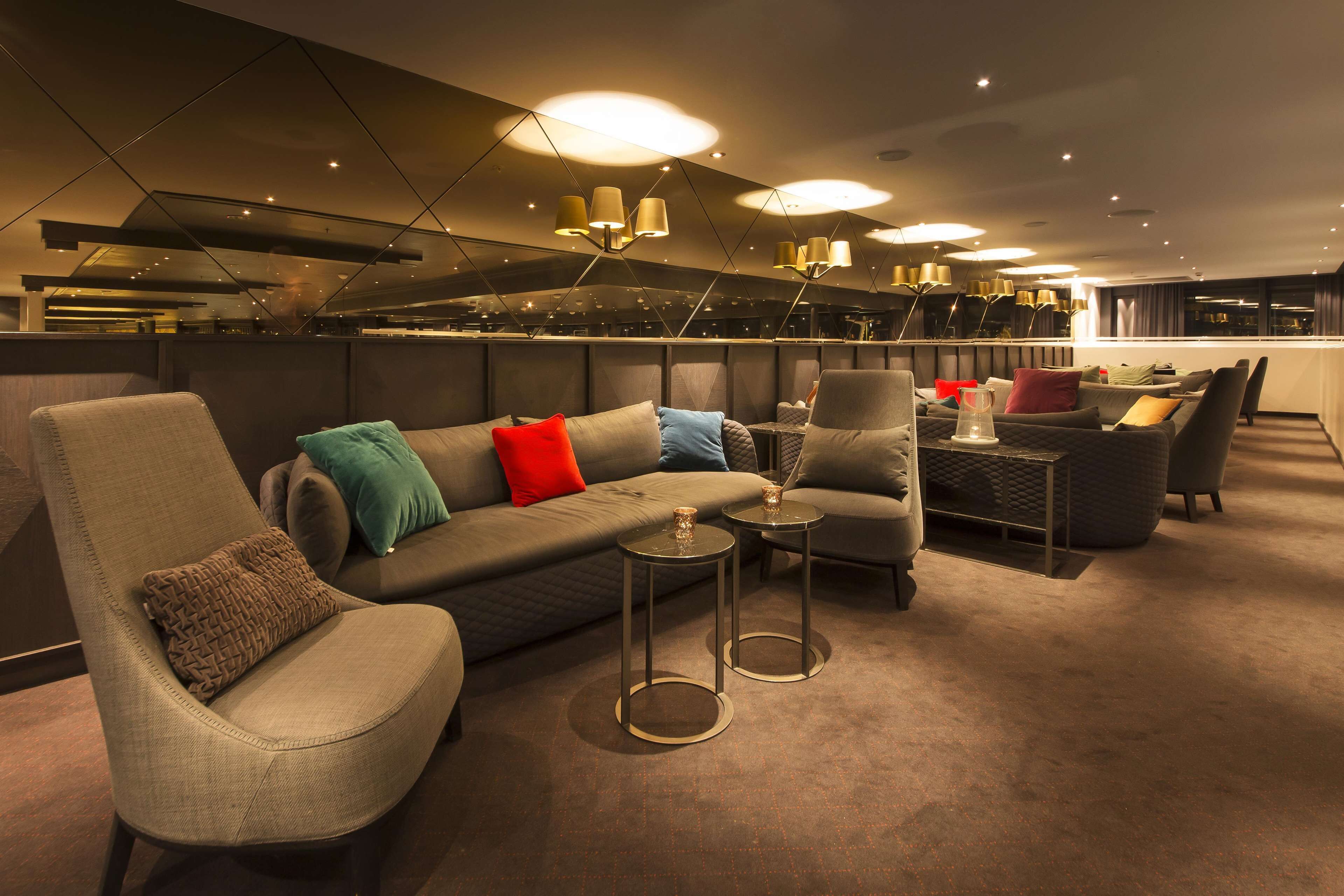A modern lounge area with a sofa set, armchairs, and a small table with a candle.