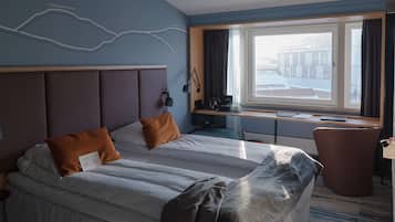 Een hotelkamer met een groot bed, een bureau en een raam met gordijnen.
