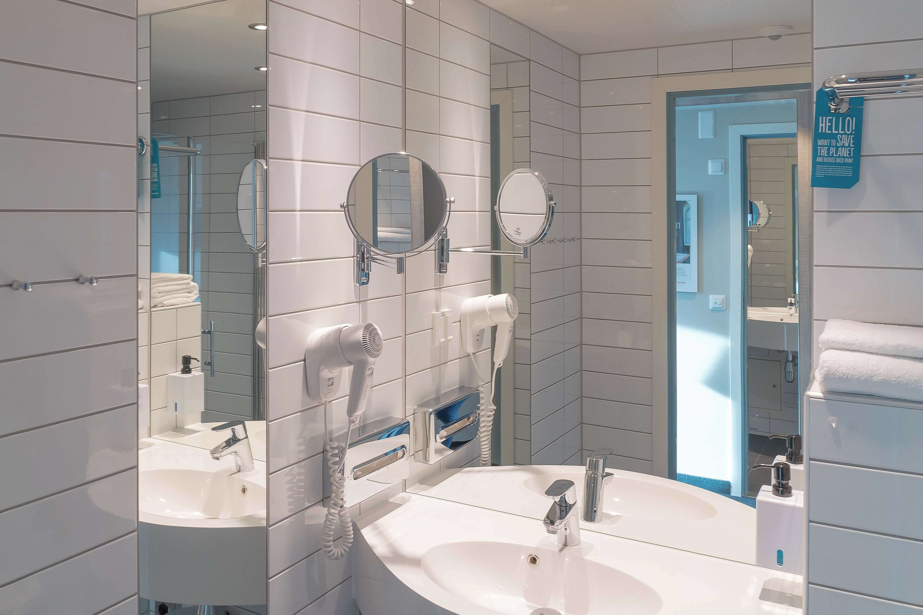 Un baño moderno con dos lavabos, un espejo grande y un perchero para toallas.