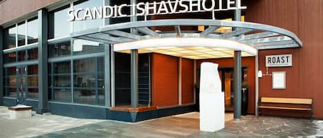El exterior del Scandic Ishavshotel, con un acceso cubierto y un banco fuera.