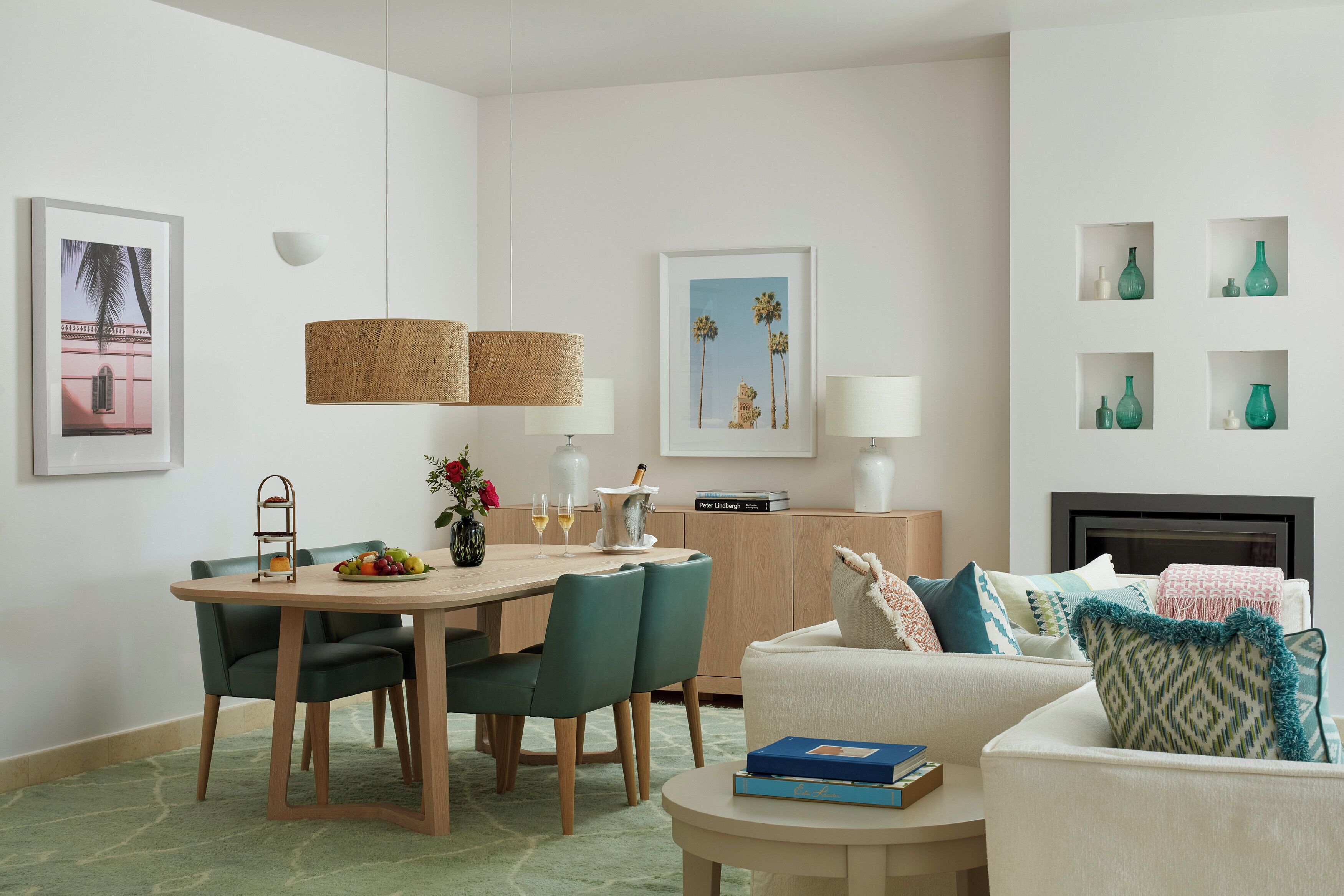 A modern living room with a dining area, featuring a wooden table, green chairs, a white sofa, and a fireplace.