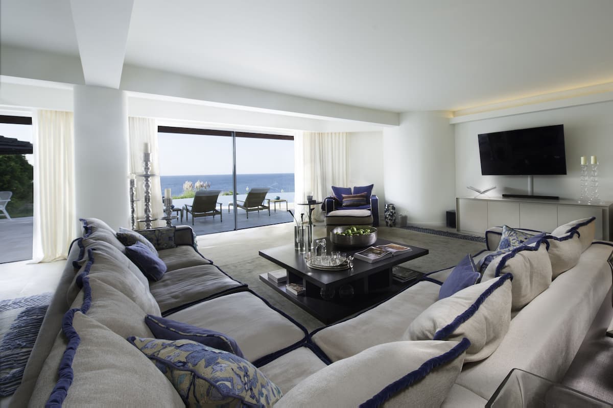 Een moderne woonkamer met een zithoek, een salontafel en een televisie. Er is een balkon met uitzicht op de oceaan.