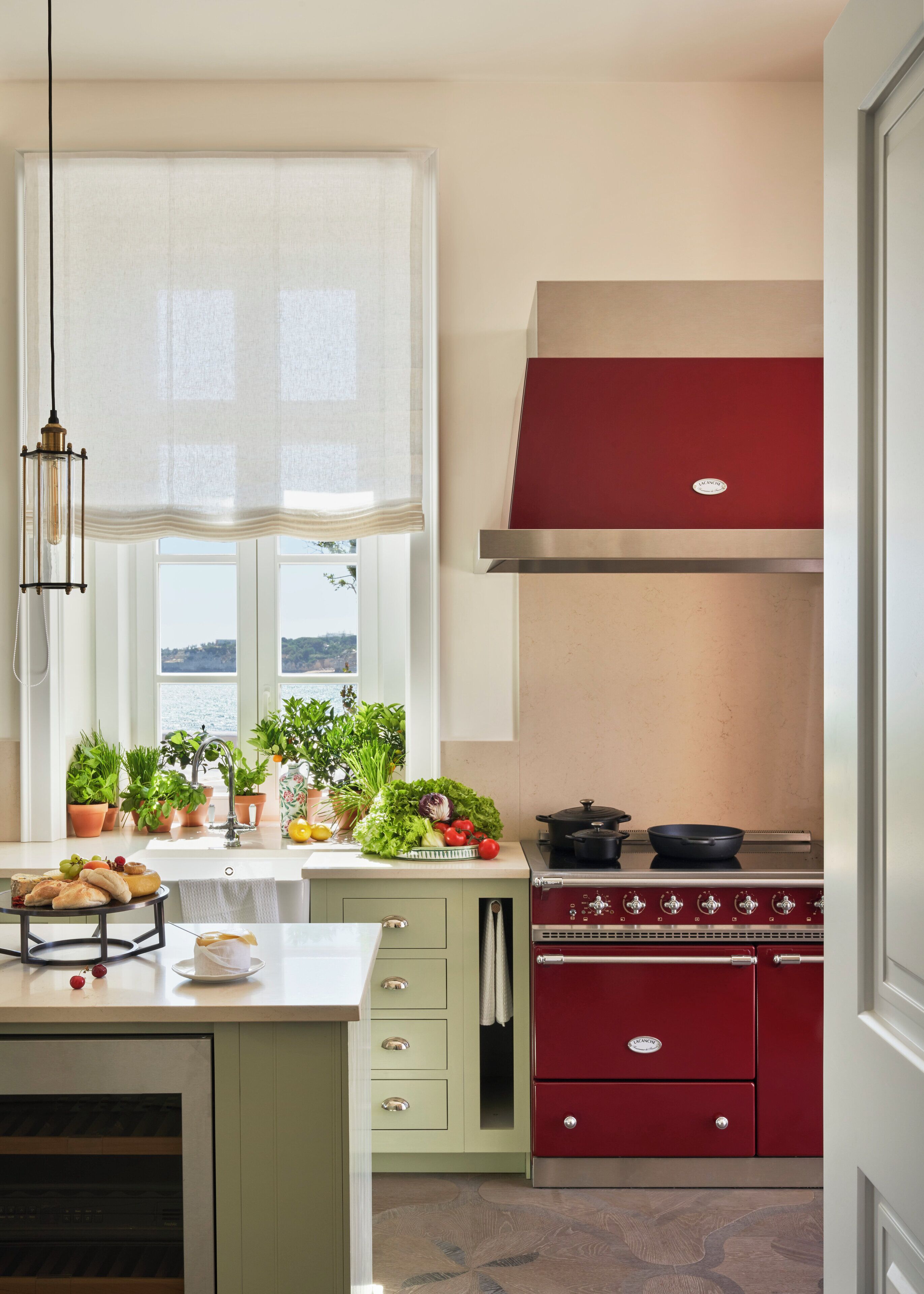 A kitchen with a red stove, a sink, and various plants on the counter.