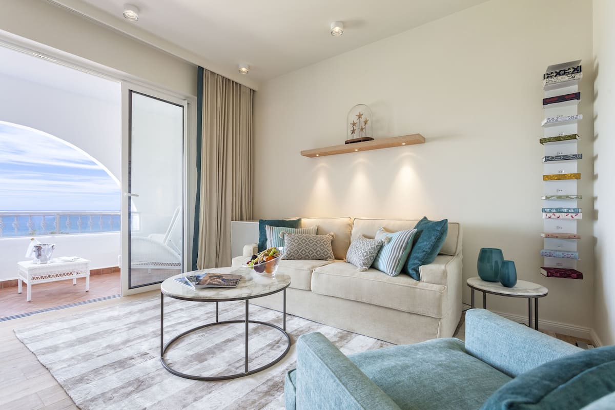 Een moderne woonkamer met een bank, fauteuils, een salontafel en een boekenkast.