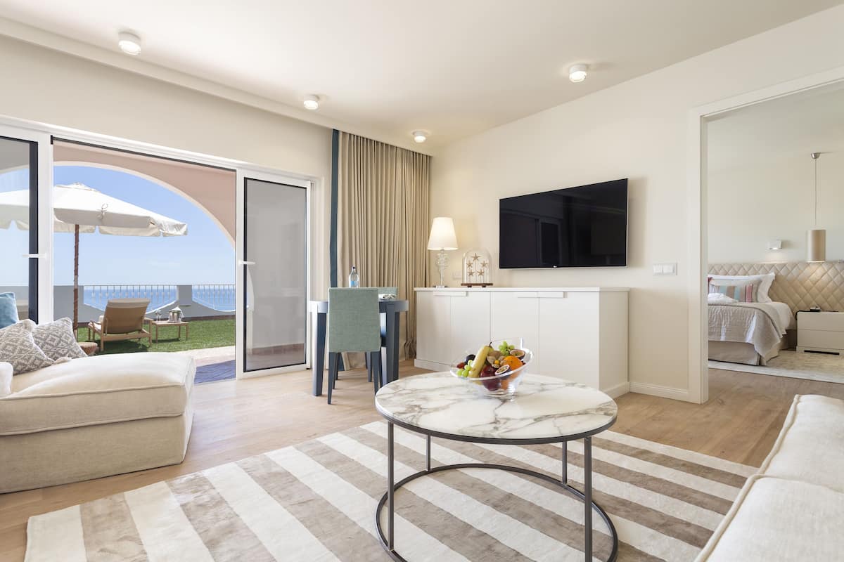 Een hotelkamer met balkon, eethoek, televisie en bed.