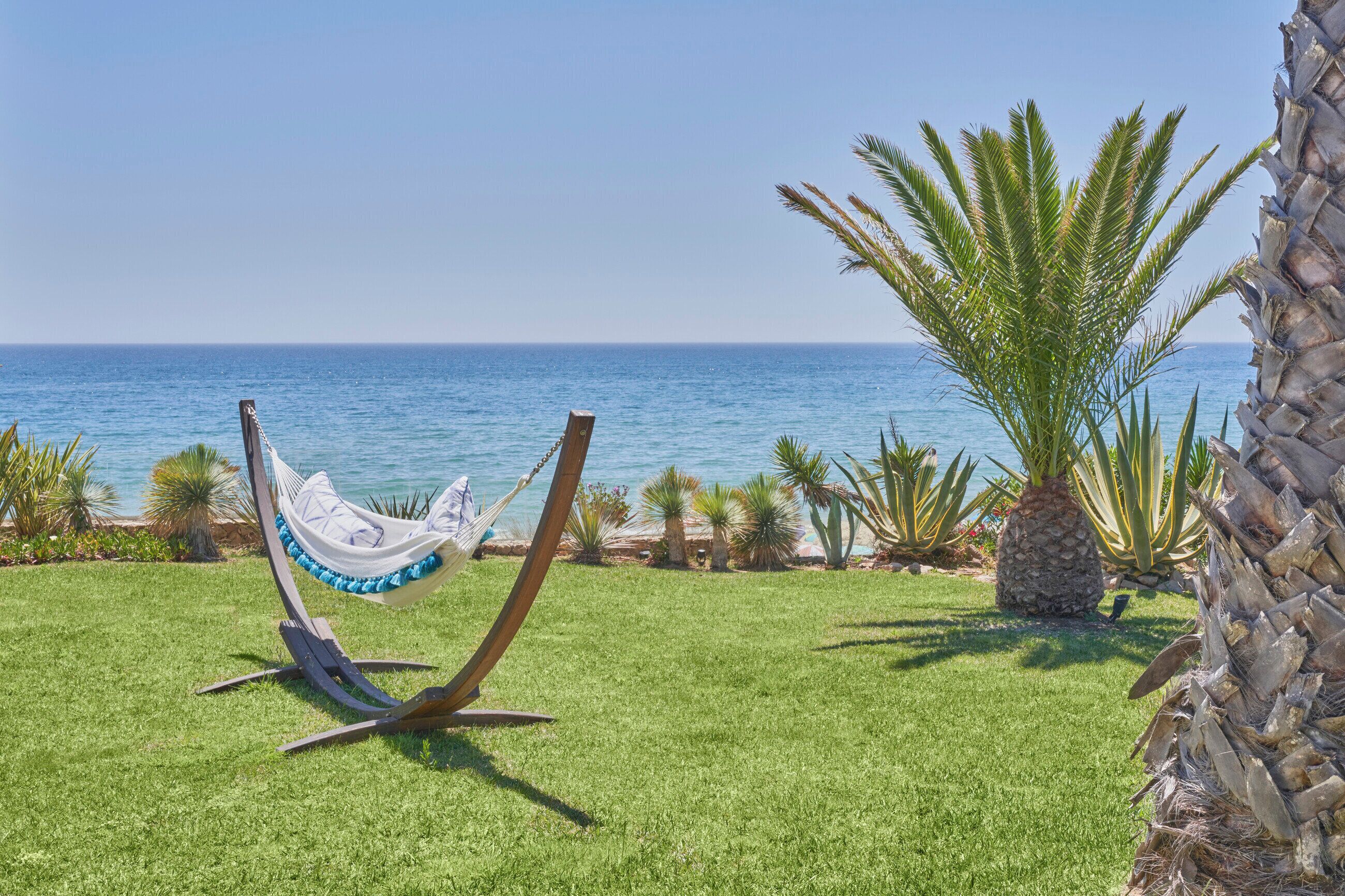 A hammock on a grassy lawn with a view of the ocean.
