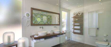 A modern bathroom with a glass shower enclosure, a large mirror, and a wooden vanity with two sinks.