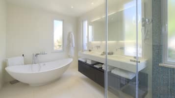 Une salle de bain moderne avec une baignoire sur pieds, un grand miroir et une douche séparée par des parois en verre.
