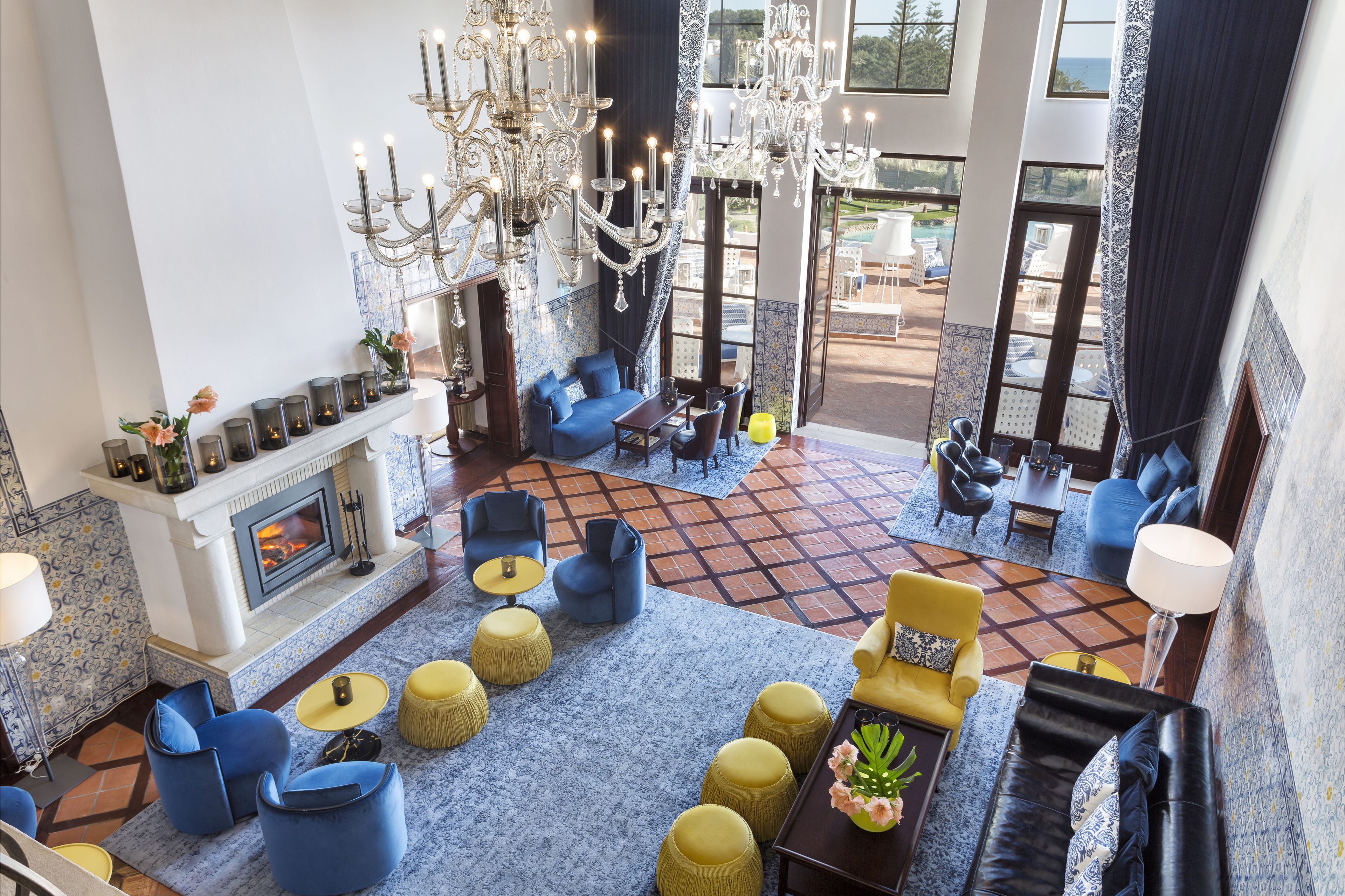 Un hall d’entrée spacieux avec une cheminée, plusieurs coins salon et un grand lustre.