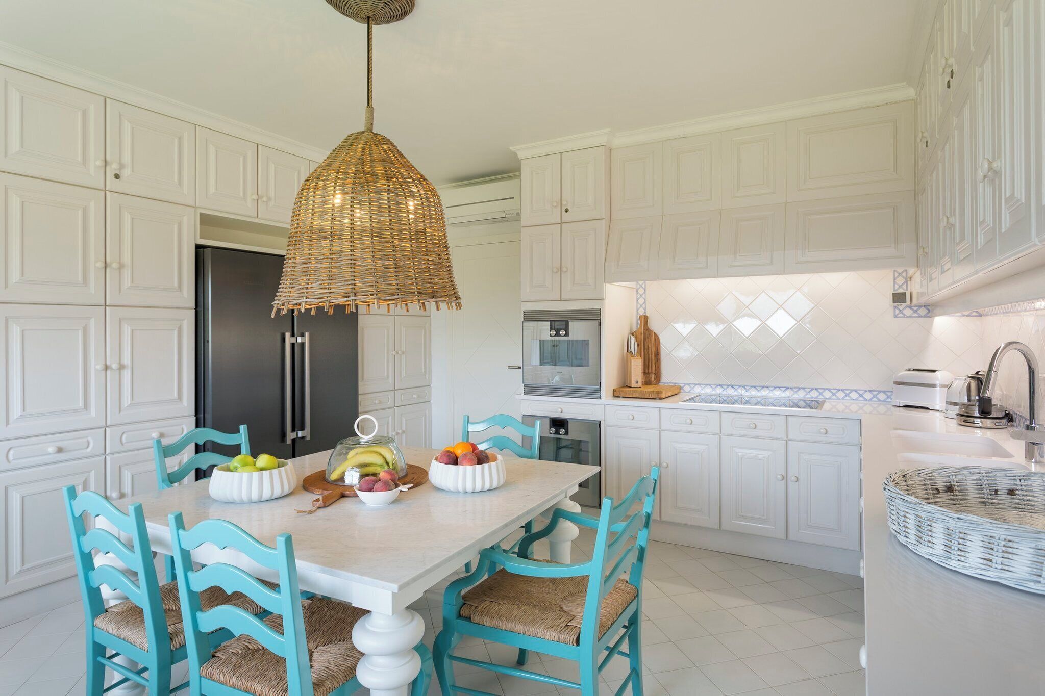 A kitchen with white cabinets, a central island, and a hanging light fixture.