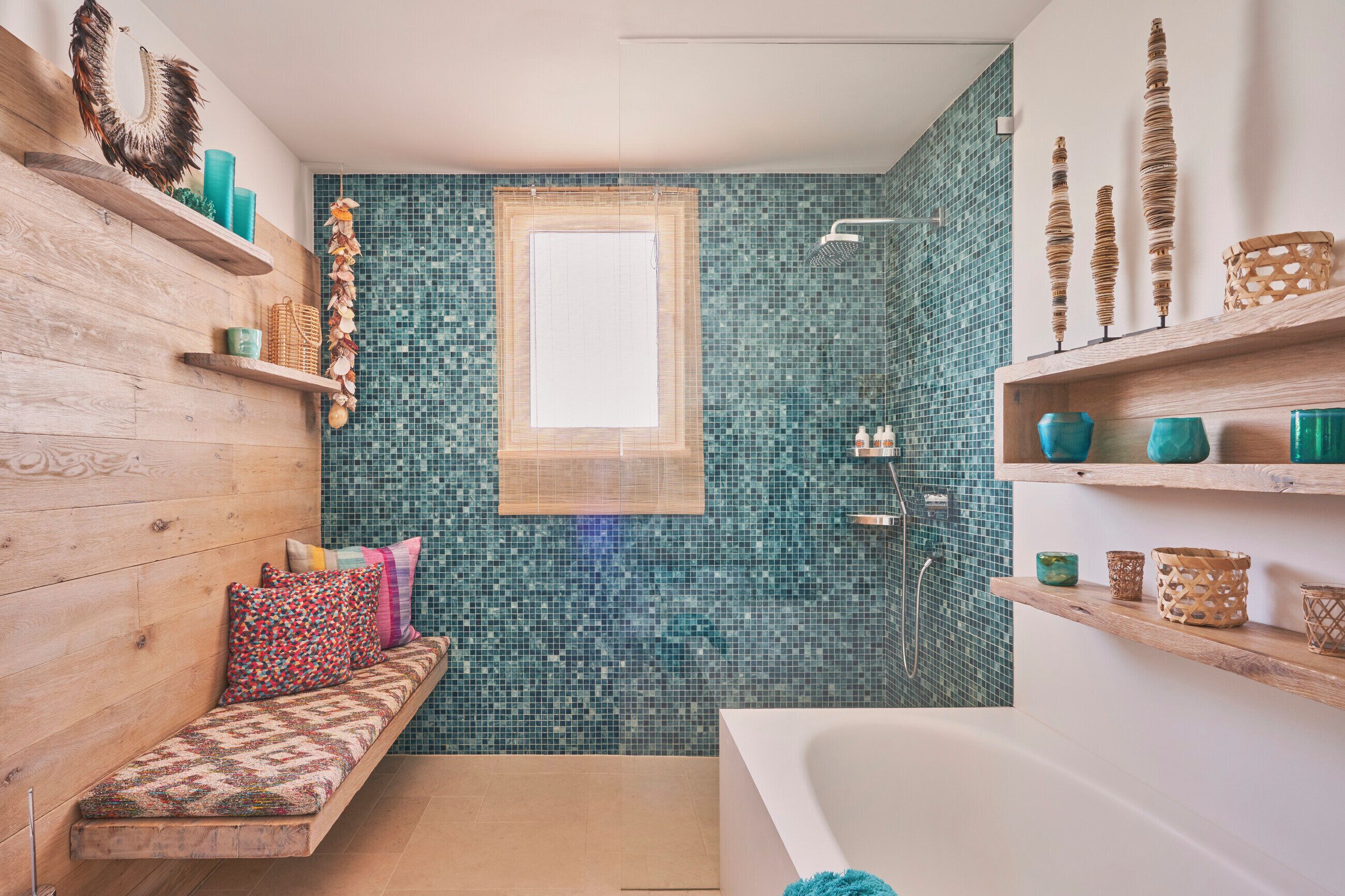 A bathroom with a wooden bench, a bathtub, and shelves with decorative items.