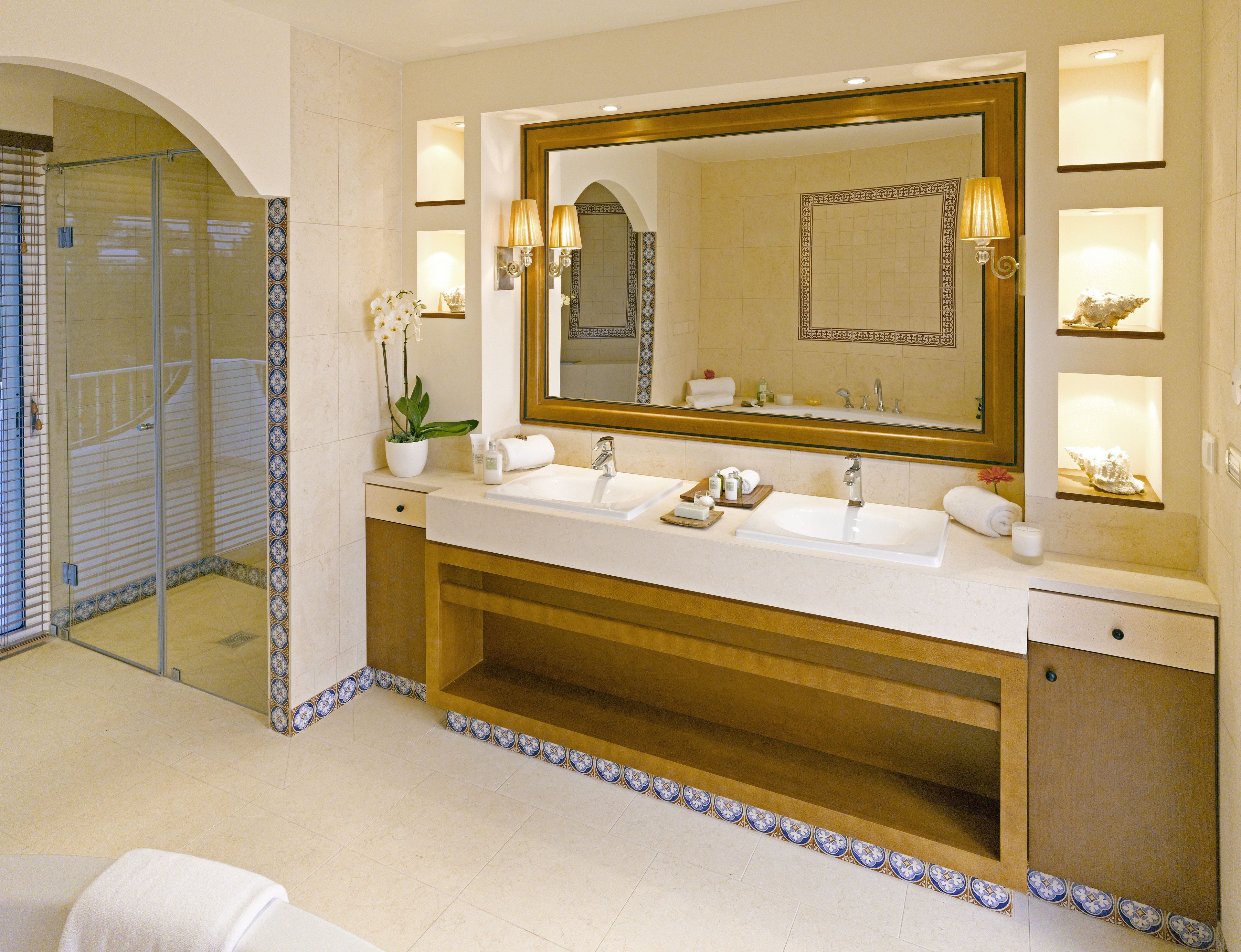 Une salle de bain luxueuse avec deux vasques, un grand miroir et une douche à l’italienne.