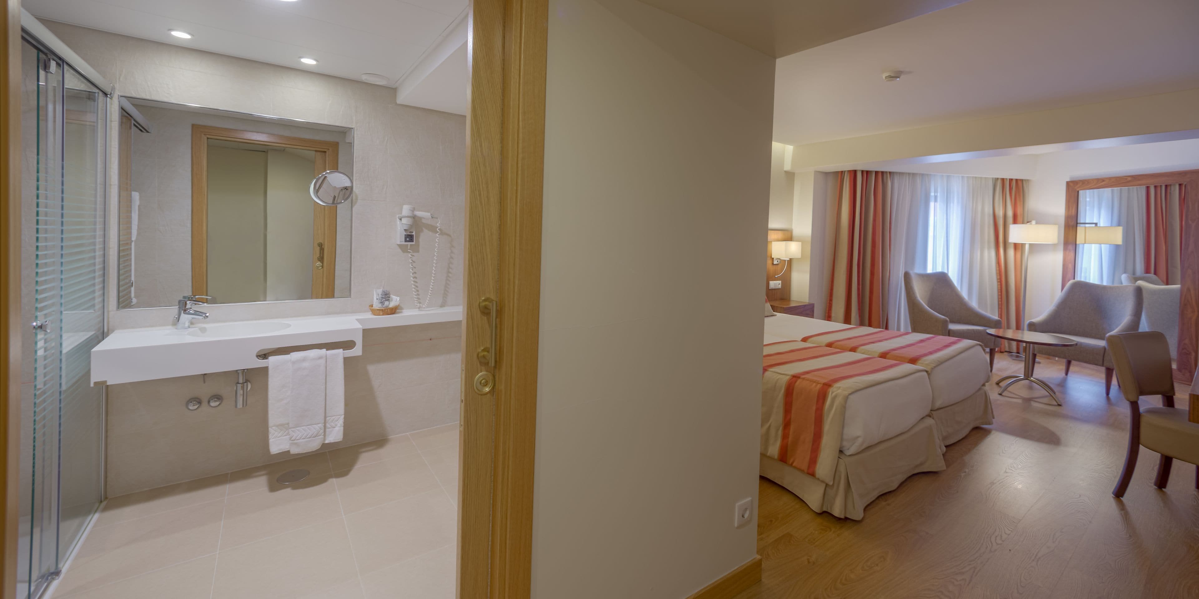 Una habitación de hotel con baño, cama, escritorio y una silla.