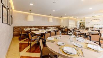 A spacious dining area with multiple tables and chairs, a central seating area with a cushioned bench, and pendant lighting.