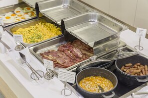 Enjoy a delicious breakfast spread with scrambled eggs, bacon, sausages, and a variety of beans.