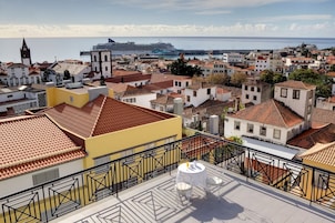 Un paysage urbain côtier caractérisé par une architecture traditionnelle, un clocher d’église imposant et un navire de croisière amarré au port.