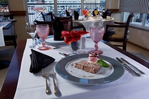 A dining table with a dessert plate, pink glassware, and a black napkin.