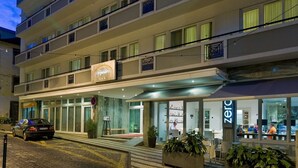 A multi-story hotel with a modern design, featuring balconies, a ground-level restaurant, and a visible sign for a bar. - Hotel Orquidea (Funchal)