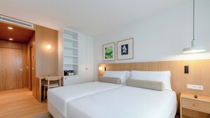 A modern hotel room with a large bed, a desk, and a wardrobe. - Hotel Orquidea (Funchal)
