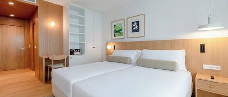 A modern hotel room with a large bed, a desk, and a wardrobe.