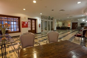 A lobby with a checkered floor, a reception desk, and a seating area with chairs and a sofa.