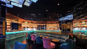 Een moderne bar met een toog, zitplaatsen en een hoge plafond met dakramen.