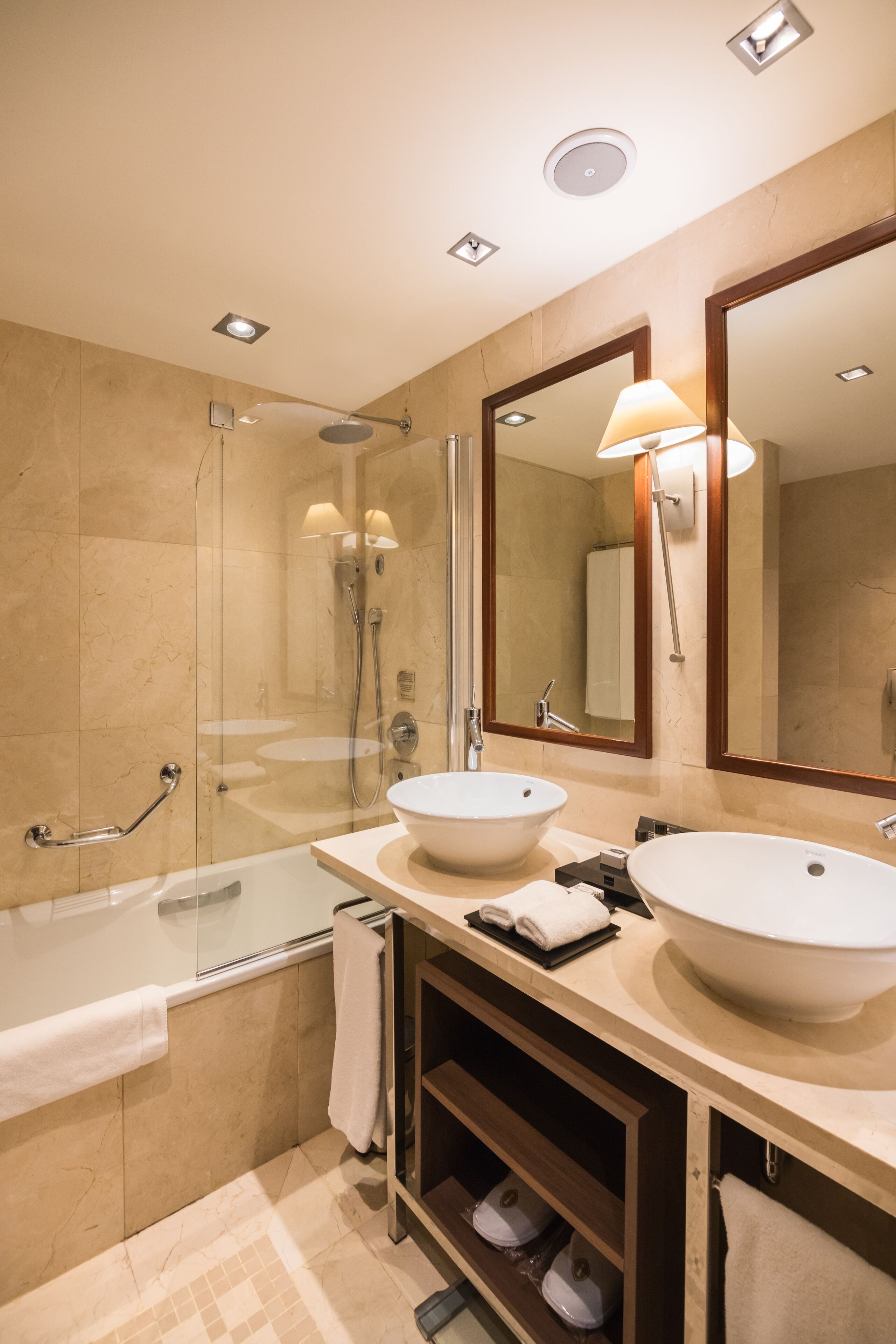 A modern bathroom with two sinks, a bathtub, a shower, and a large mirror.
