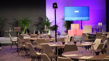Un salón de conferencias con mesas y sillas, una pantalla grande mostrando 'LUNCH' y un cartel que dice 'Q&A Spot'.