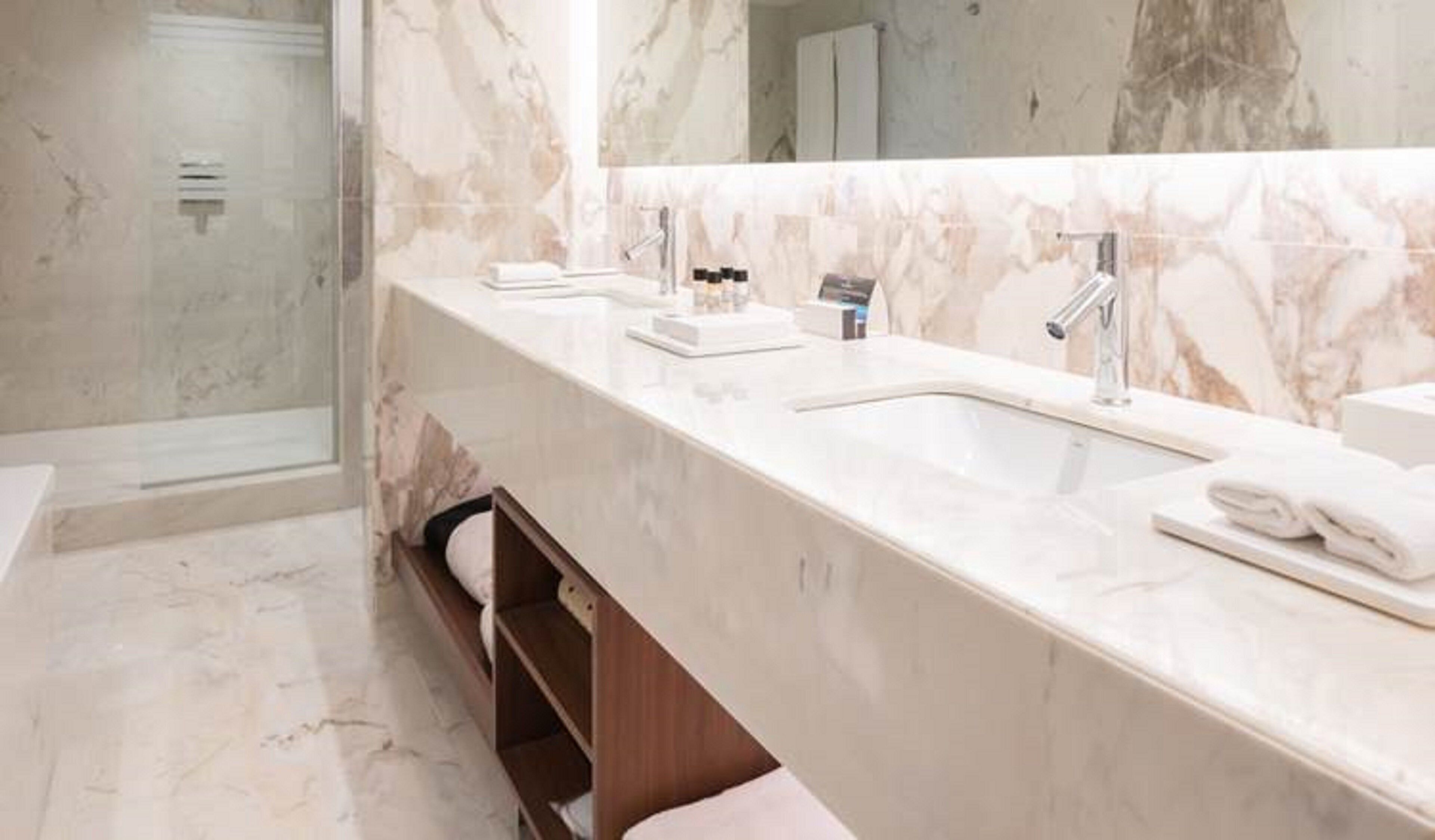 Un baño moderno con tocador de mármol, cabina de ducha de vidrio y un espejo grande.