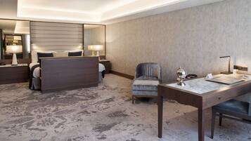 Relax in a spacious room with a large bed, seating area, and desk, perfect for work or relaxation.