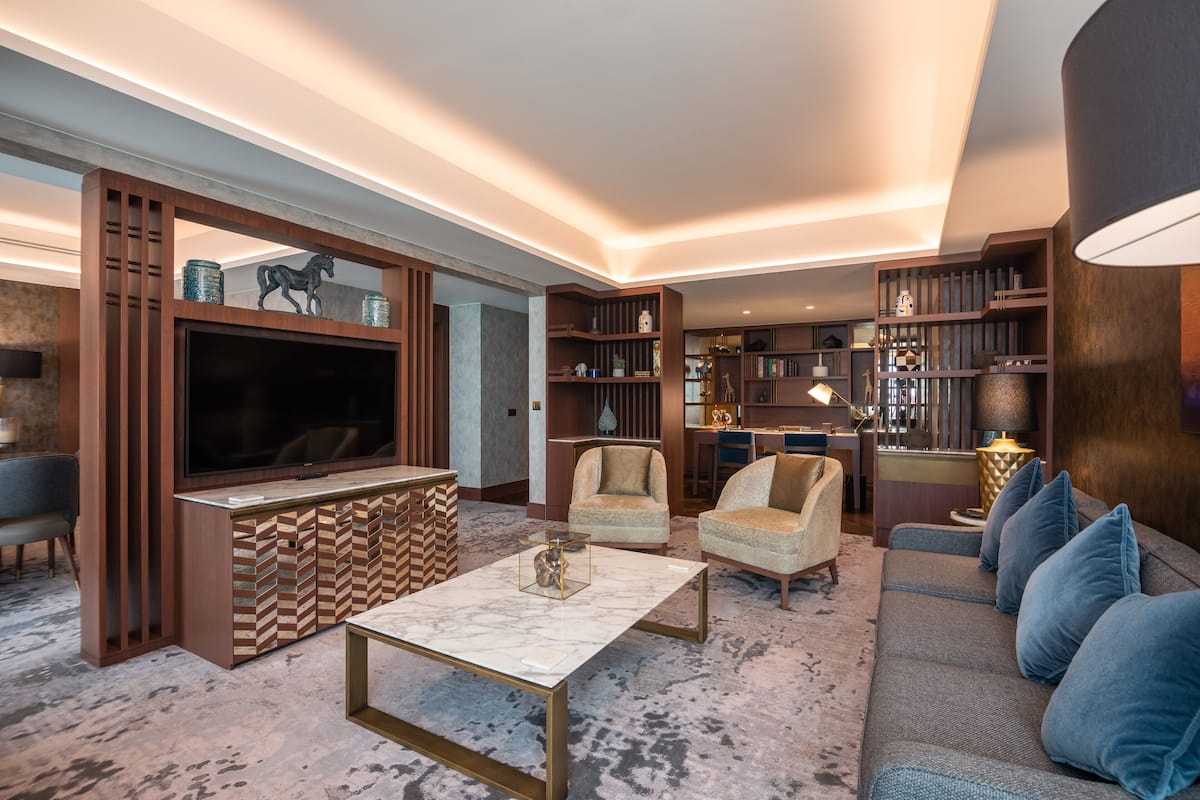 A modern living room with a television, sofas, armchairs, a coffee table, and a bookshelf.