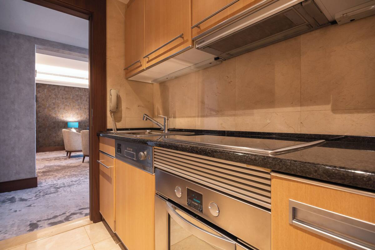 A modern kitchen with stainless steel appliances, wooden cabinets, and a black granite countertop.