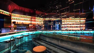 A bar area with a sofa, stools, and a bar counter.