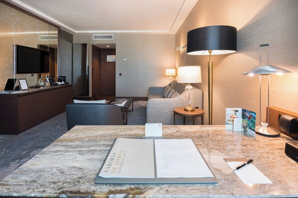 A hotel room with a marble reception desk, a sofa, a small table, and a lamp. - InterContinental Lisbon by IHG (Lisbon)