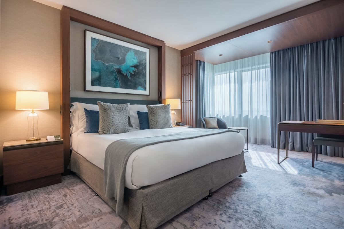 A hotel room with a large bed, a desk, and a view of the outdoors.