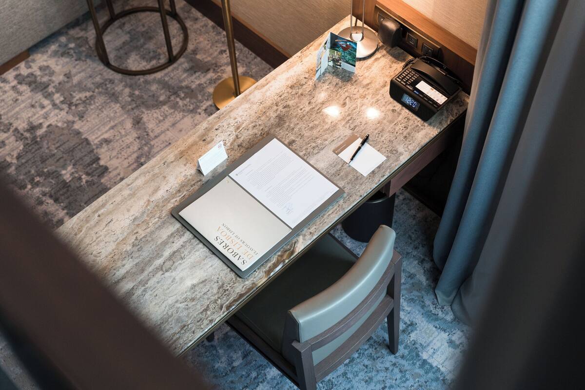 A hotel reception desk with a marble top, a telephone, a notepad, and a pen.