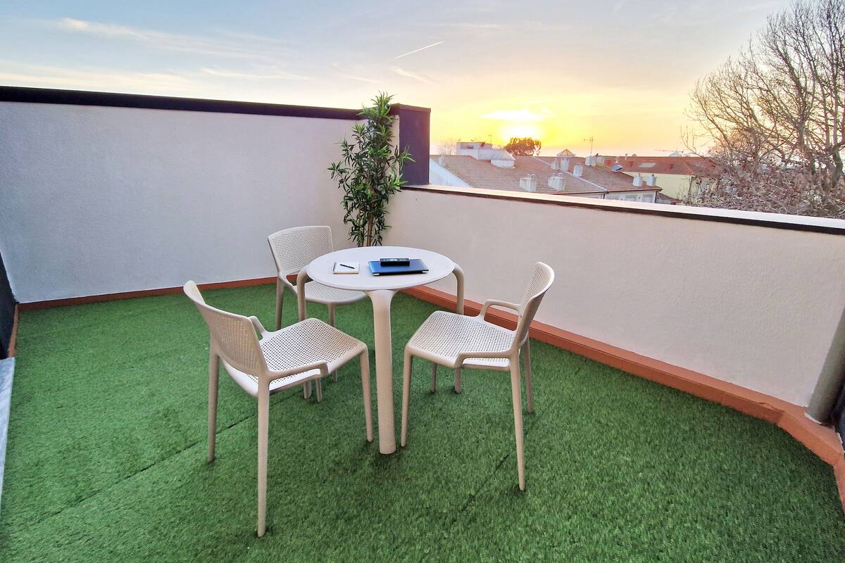 A balcony with artificial grass, a round table, and four chairs.