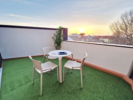 A balcony with artificial grass, a round table, and four chairs.